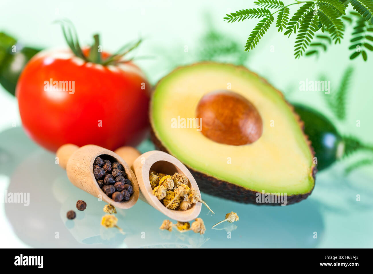Makro Nahaufnahme Stillleben von naturheilkundlichen Produkten. Avocado mit Kräuter und Samen vor grünem Hintergrund. Stockfoto