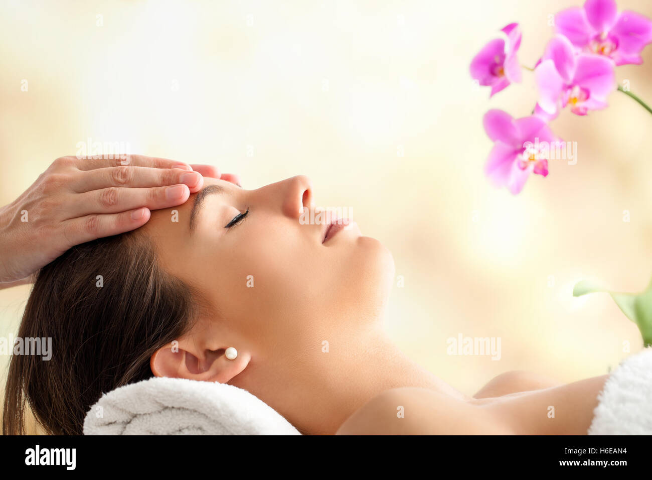 Porträt der jungen weiblichen Gesichts-Massage im Spa hautnah. Therapeuten massieren Frauenkopf vor hellen bunten Hintergrund. Stockfoto