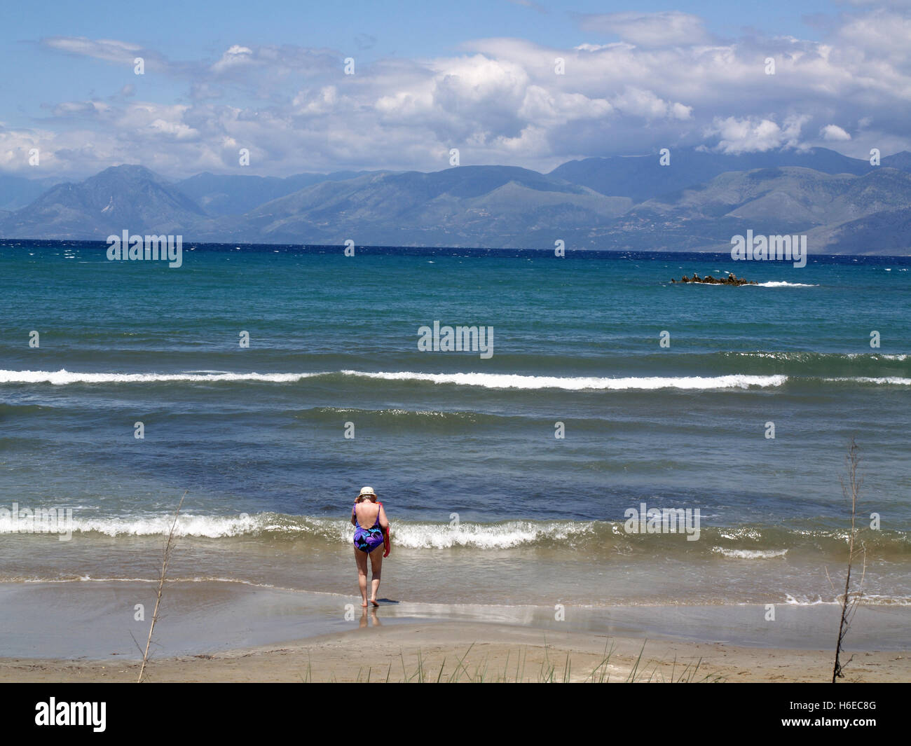 Nur ungern Dame Badende St. Spiridon Beach, Korfu Griechenland mit Blick auf die Berge von Albanien Stockfoto