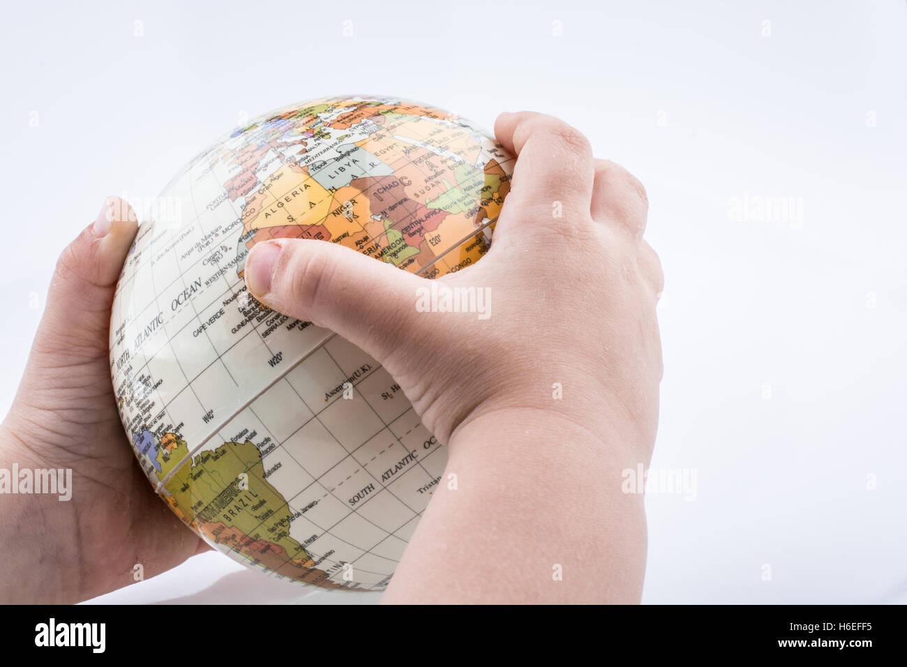 Kind mit einem Globus in der Hand auf einem weißen Hintergrund Stockfoto