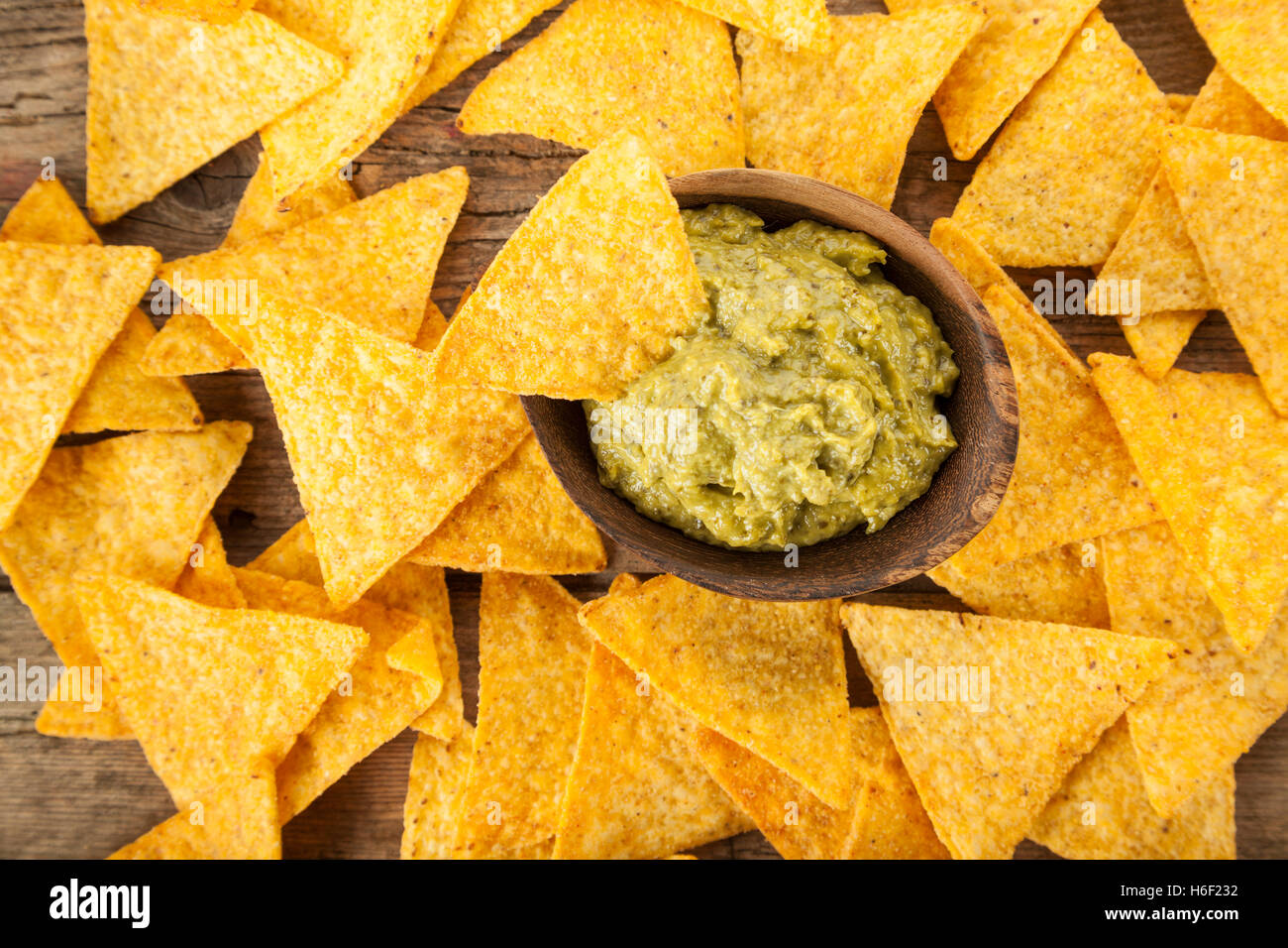 Guacamole Salsa in Holzschale umgeben von Tortilla-Chips, erhöhte Ansicht Stockfoto