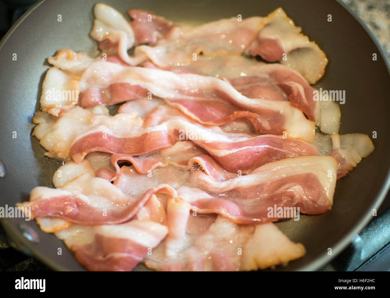 Rohes Schweinefleisch Speckstreifen wird Fried in ein Teflon Pfanne Close Up Stockfoto