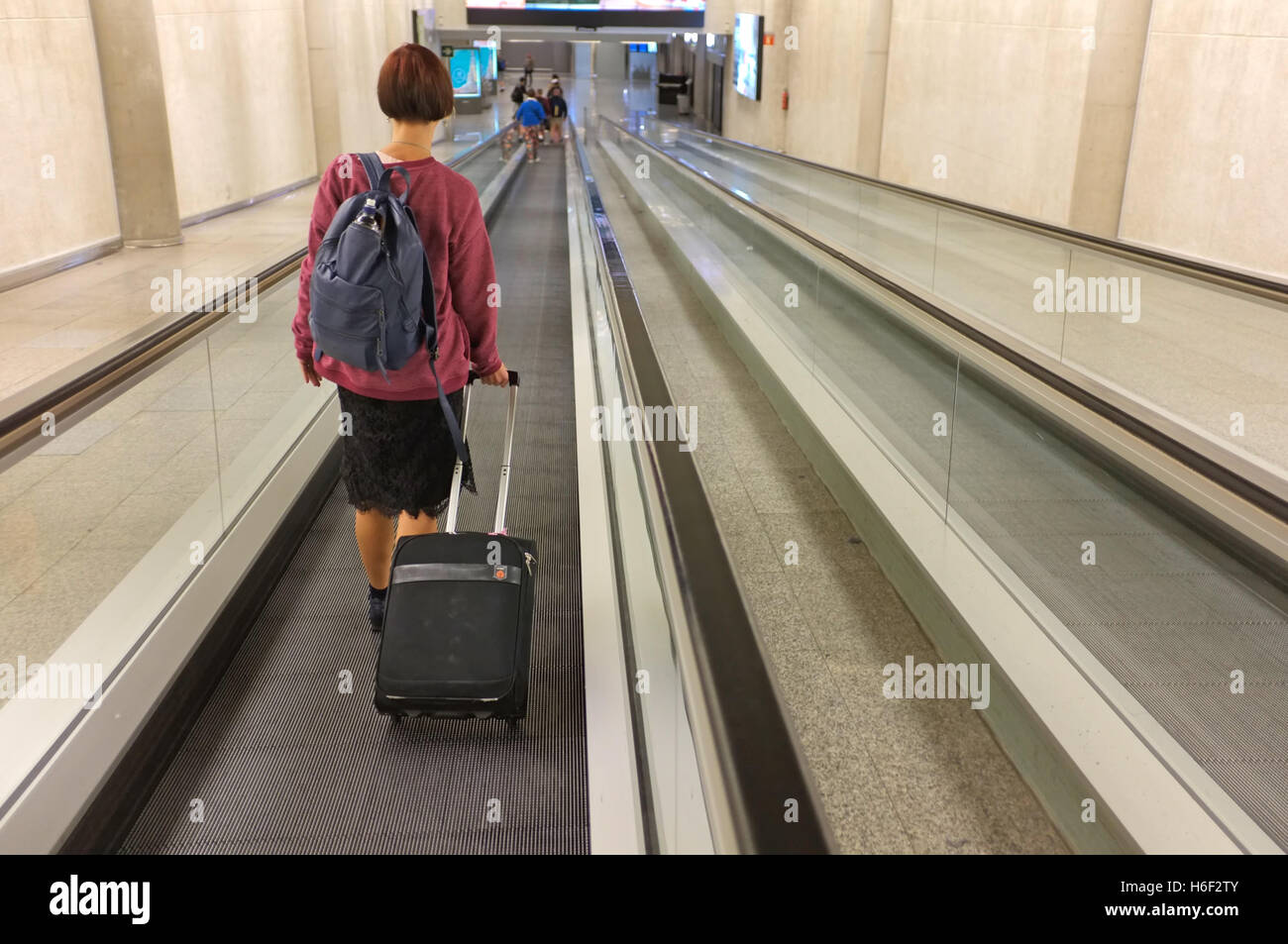 Eine Frau auf einem Travelator am Flughafen von Palma auf Mallorca. Stockfoto