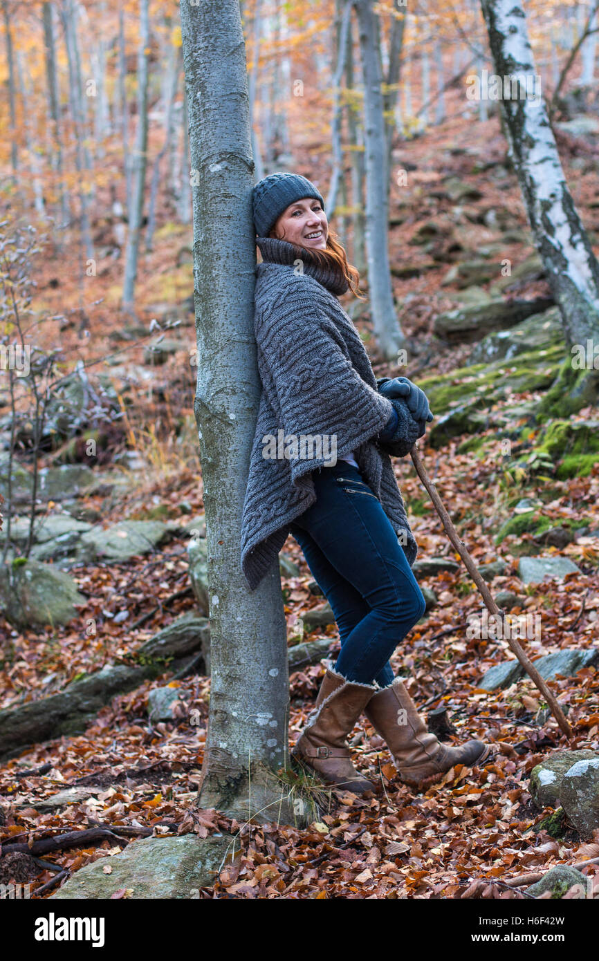 Eine glamouröse Frau Wandern durch die Wälder im Herbst fallen Saison eine lockere Wolle Poncho Freizeit Wollmütze Handschuhe tragen Stockfoto