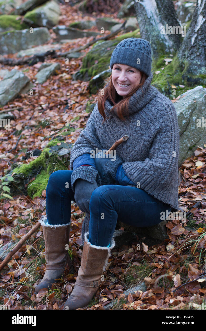 Eine glamouröse Frau Wandern durch die Wälder im Herbst fallen Saison tragen eine lockere Wolle Poncho Freizeitbekleidung, Wollmütze Stiefel Stockfoto