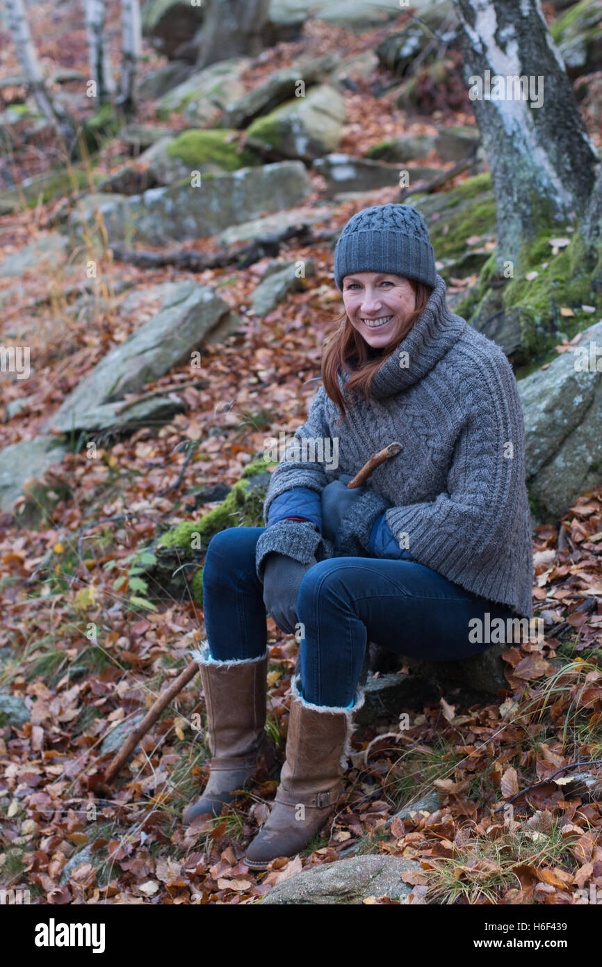 Eine glamouröse Frau Wandern durch die Wälder im Herbst fallen Saison tragen eine lockere Wolle Poncho Freizeitbekleidung, Wollmütze Stiefel Stockfoto