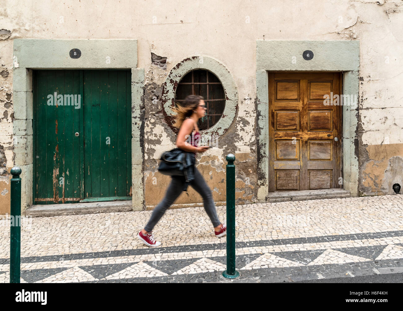 Junge Frau, die vorbei an alten Gebäude/Türen in Funchal, Madeira Stockfoto