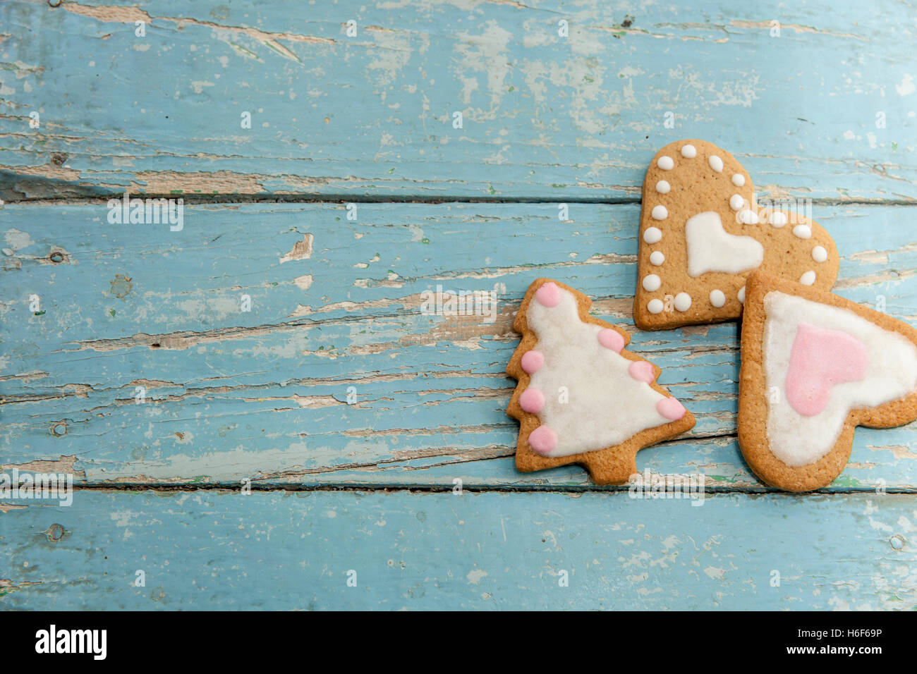 Winter-Lebkuchen mit handgefertigten Sahnehäubchen auf einem blauen Holztisch. Herzförmige, sternförmigen und Weihnachtsbaum geformt. Stockfoto