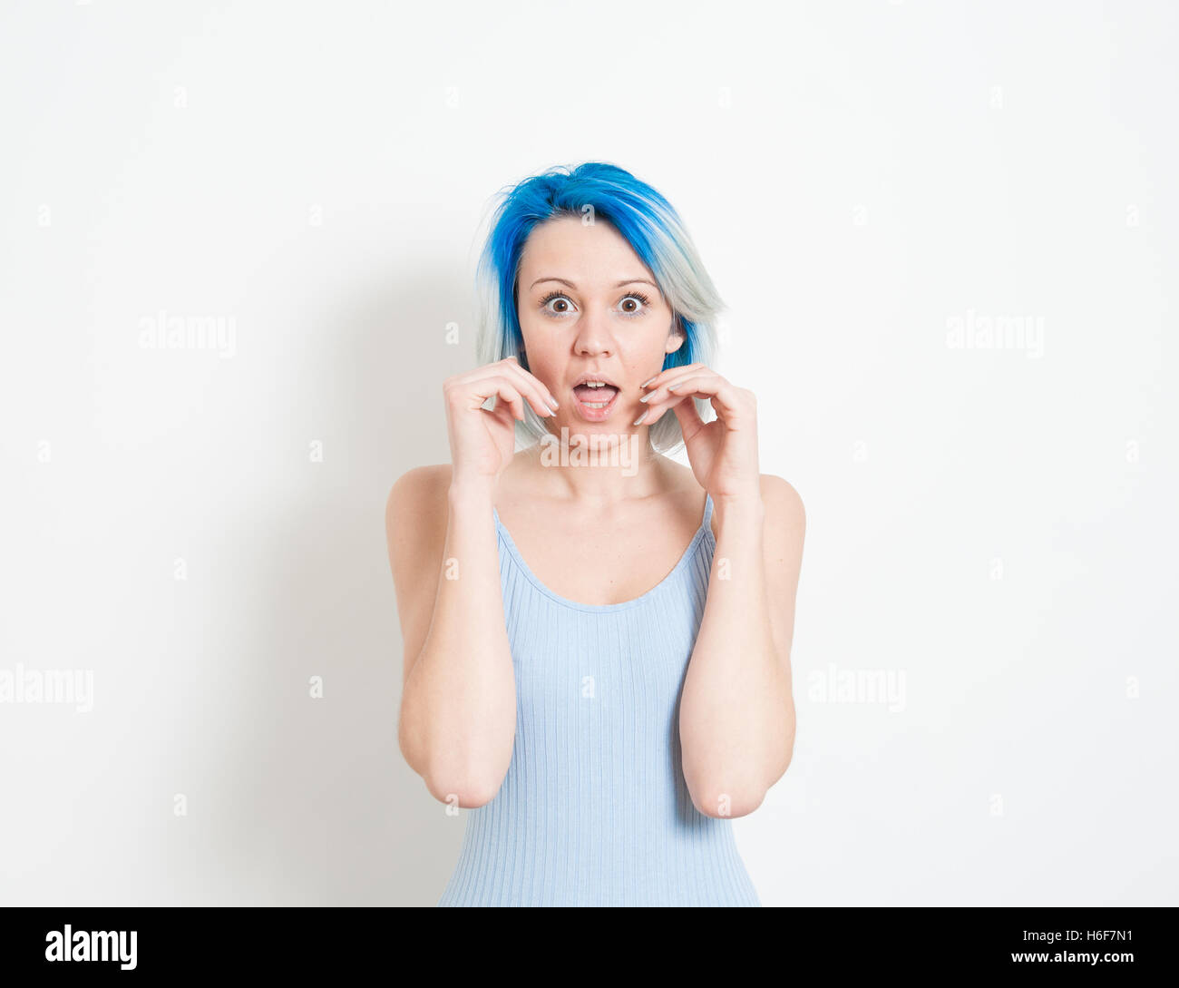 Junge schöne blaue Haare alternative Hipster Frau betäubt Ausdruck Blick in die Kamera mit der Hand den Mund auf weiße Rückseite Stockfoto