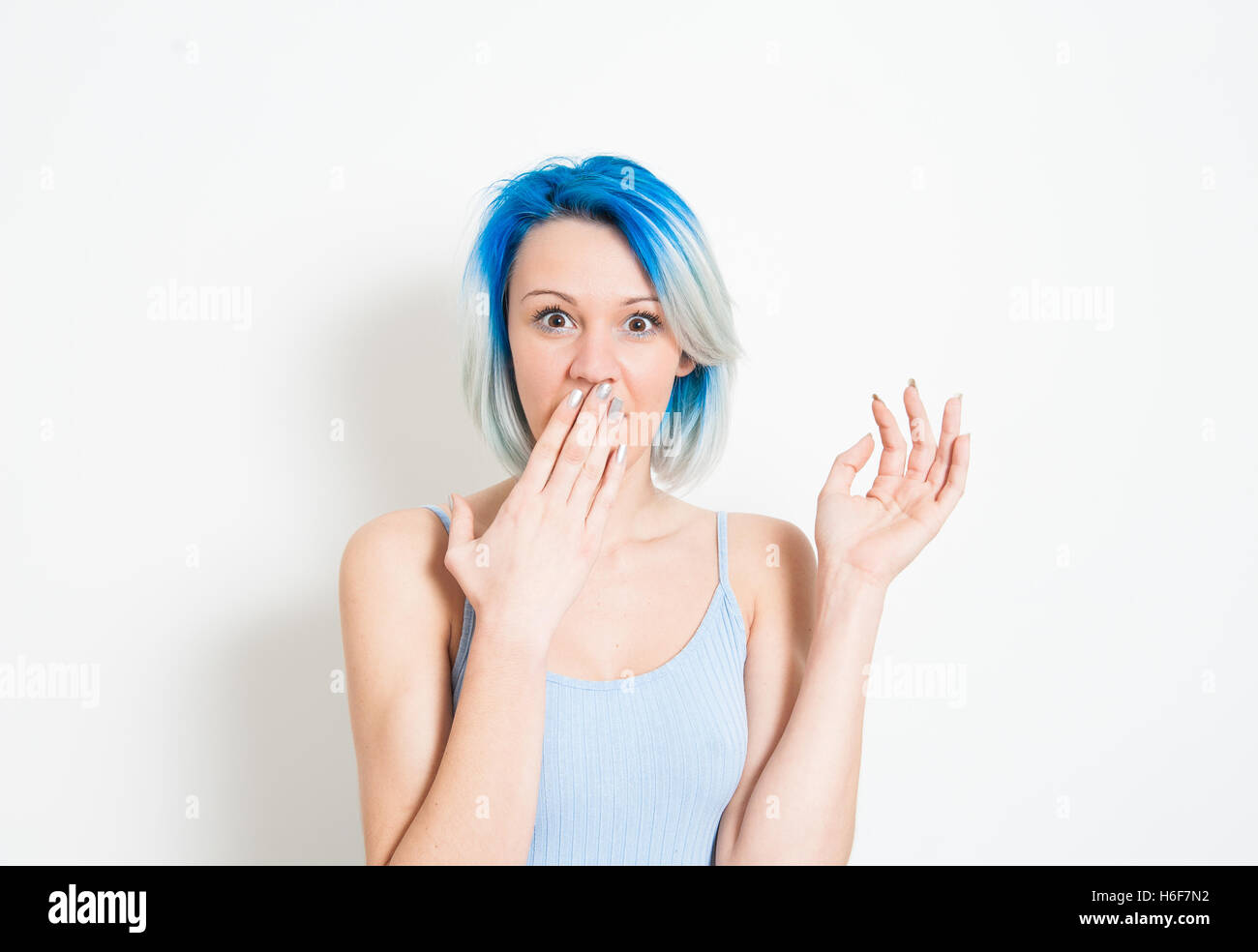 Junge schöne blaue Haare alternative Hipster Frau betäubt Ausdruck Blick in die Kamera mit der Hand den Mund auf weiße Rückseite Stockfoto