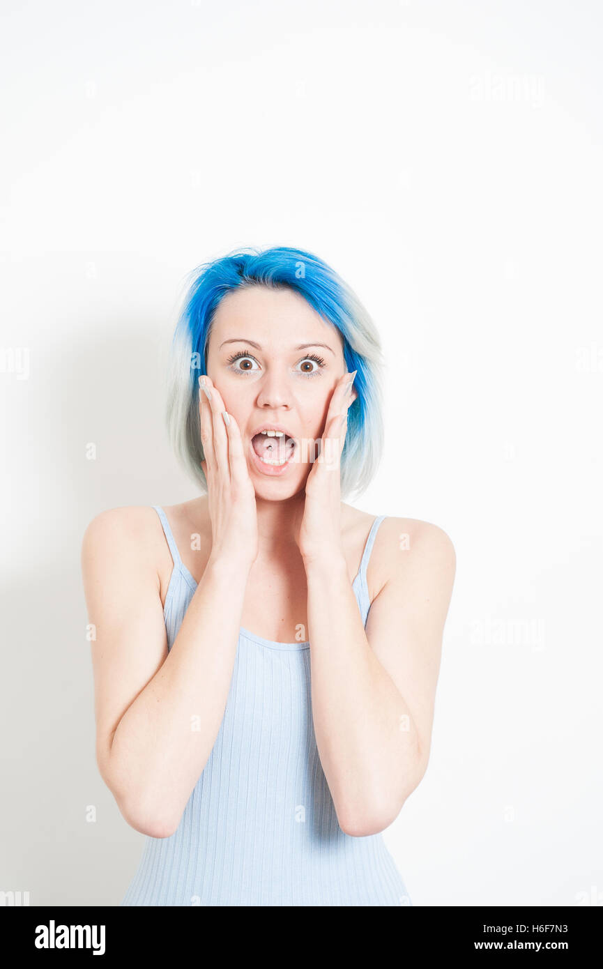 Junge schöne blaue Haare alternative Hipster Frau betäubt Ausdruck Blick in die Kamera mit der Hand um Mund auf weißen backgr Stockfoto