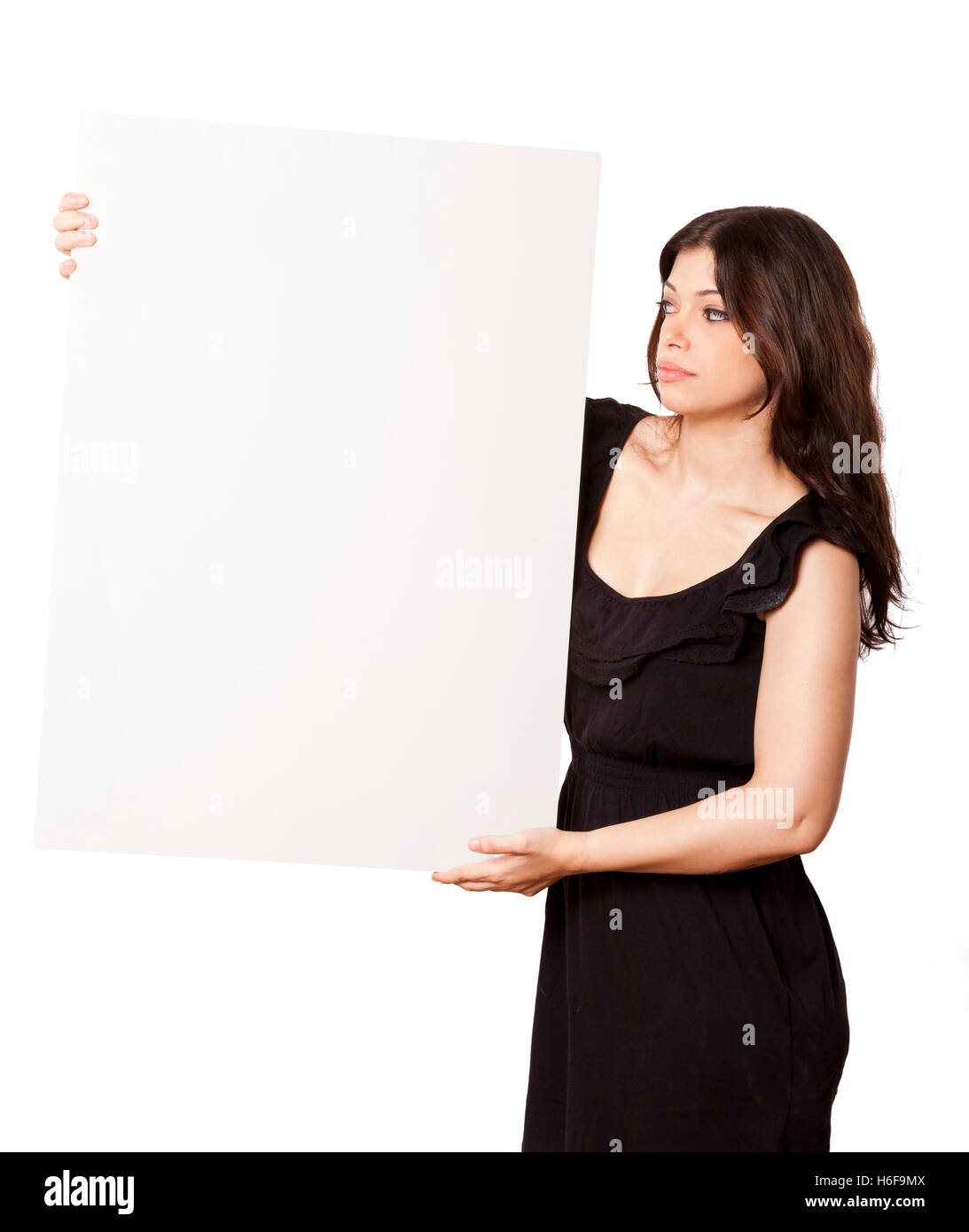Schöne junge Erwachsene kaukasischen Frau in ihrer Mitte 20 mit Blick auf das leere weiße Zeichen, die sie mit beiden Händen hält. Isoliert auf Stockfoto