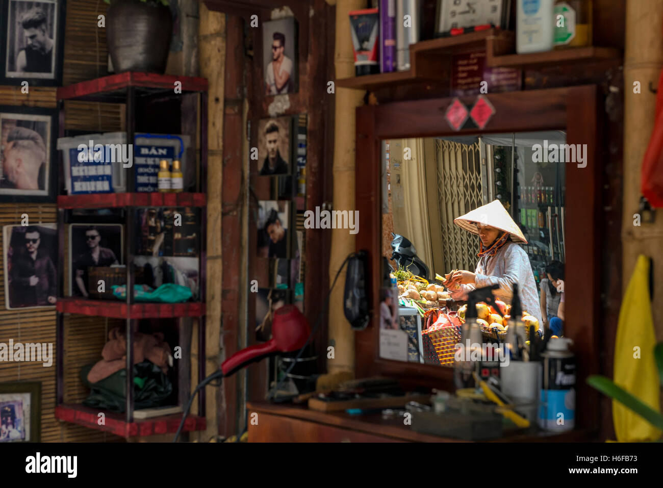 Reflexion von einem Obst-Verkäufer auf dem Spiegel einen Friseurladen in einer Straße von Hanoi. Stockfoto