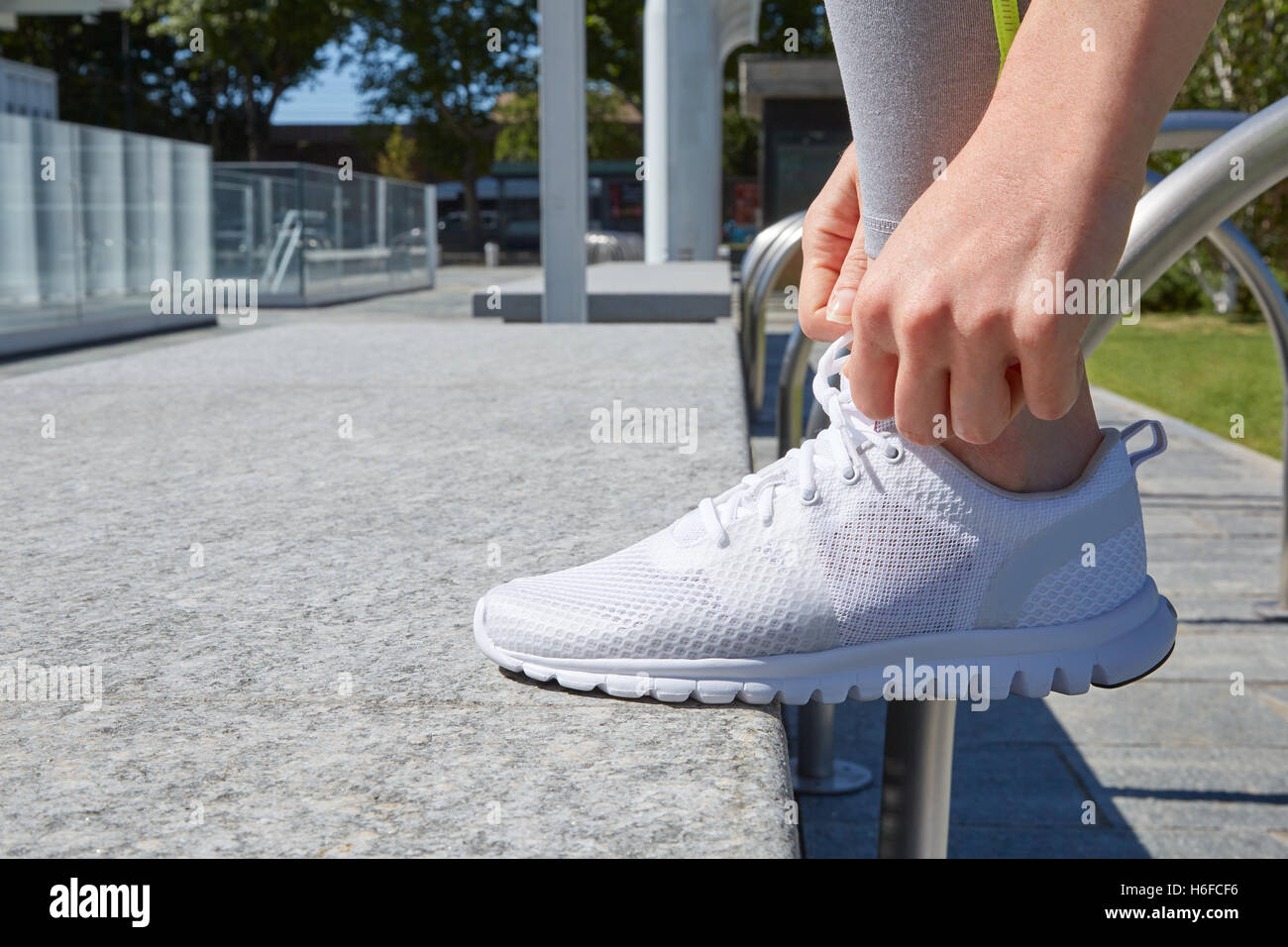 Frau, die Schnürsenkel zu binden, bevor Sie ausführen, weißen Schuh im Sonnenlicht Stockfoto