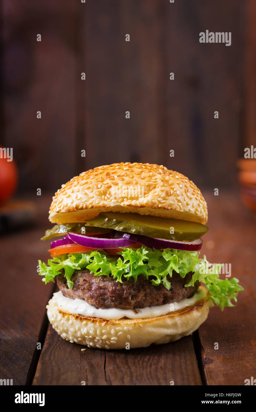 Big Sandwich - Hamburger Burger mit Rindfleisch, Gurken, Tomaten und Tartar sauce auf hölzernen Hintergrund. Stockfoto
