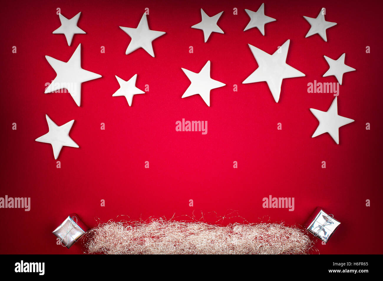 Hintergrund - weiße Weihnachtssterne auf einem roten Hintergrund mit silbernen Engelshaar und Xmas-Geschenke Stockfoto
