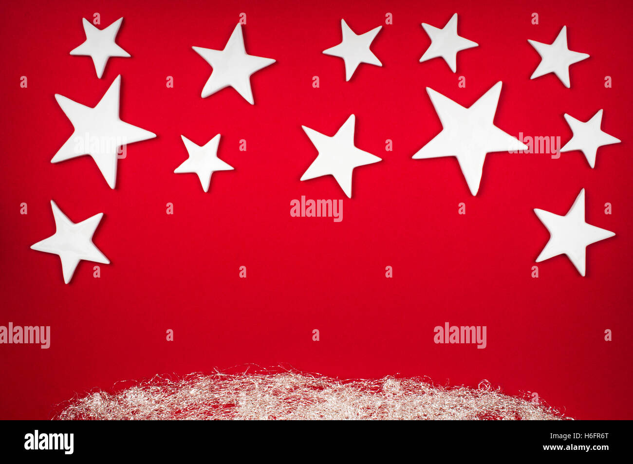 Hintergrund - weiße Weihnachtssterne auf einem roten Hintergrund mit silbernen Engelshaar und Exemplar Stockfoto