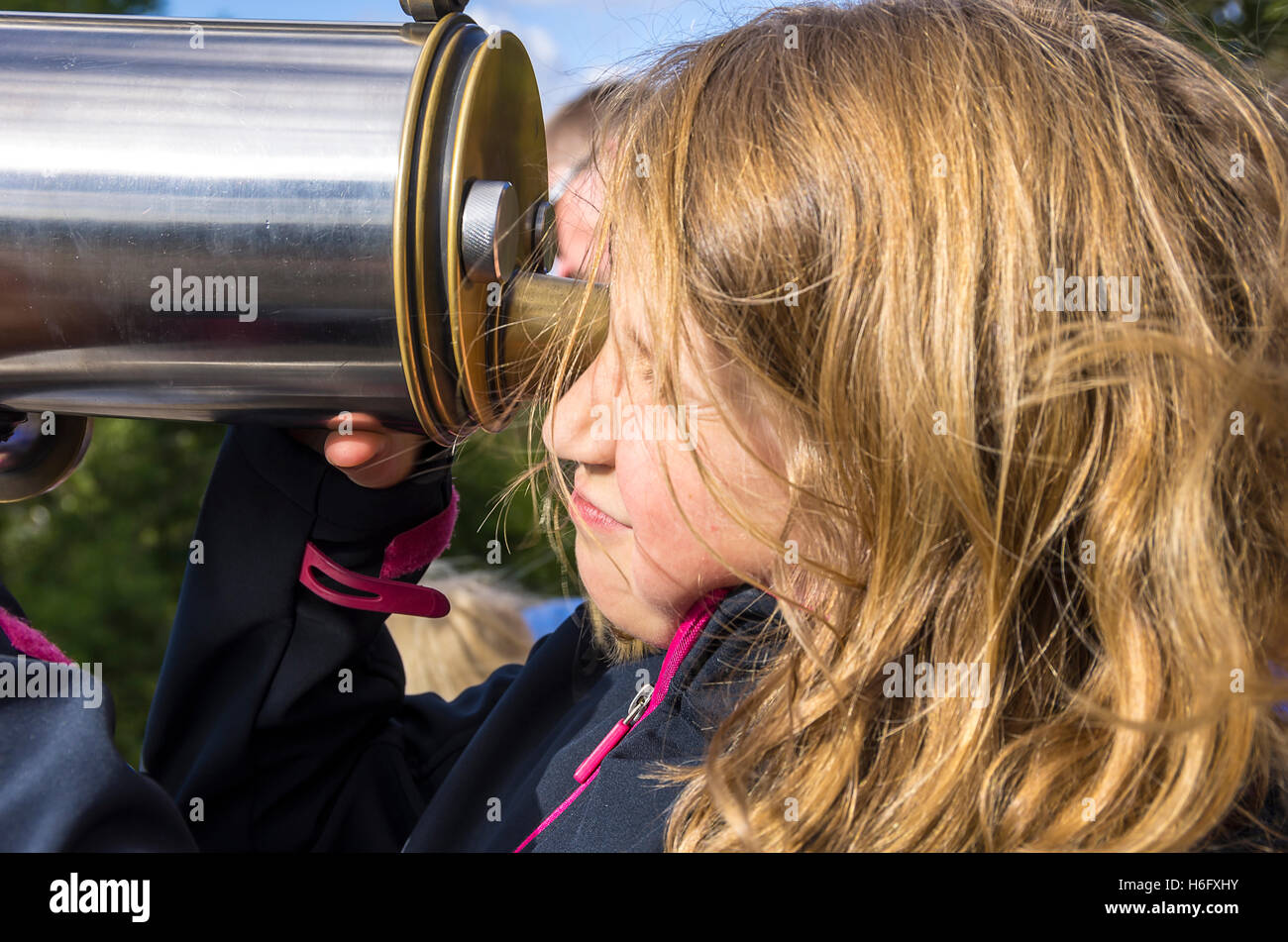 Acht Jahre altes Mädchen durchsucht ein Teleskop. Stockfoto