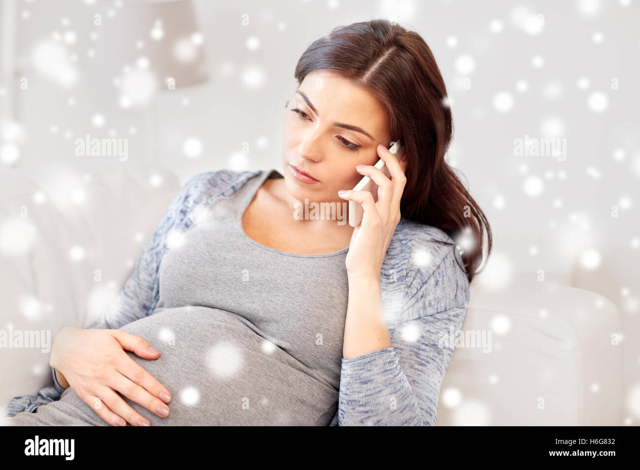 traurig schwangere Frau fordert Smartphone zu Hause Stockfoto