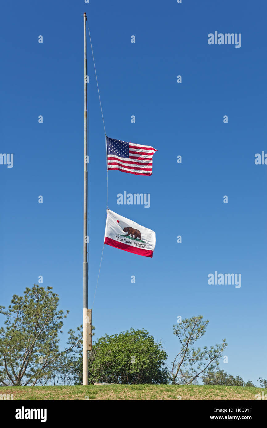 USA und California Fahnen auf Halbmast auf einem Hügel oben mit blauem Himmelshintergrund Stockfoto
