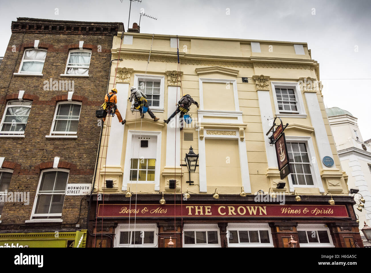 Maler und Dekorateure, die das Äußere des öffentlichen Hauses Crown in der Monmouth Street, London, WC2 abseilen Stockfoto