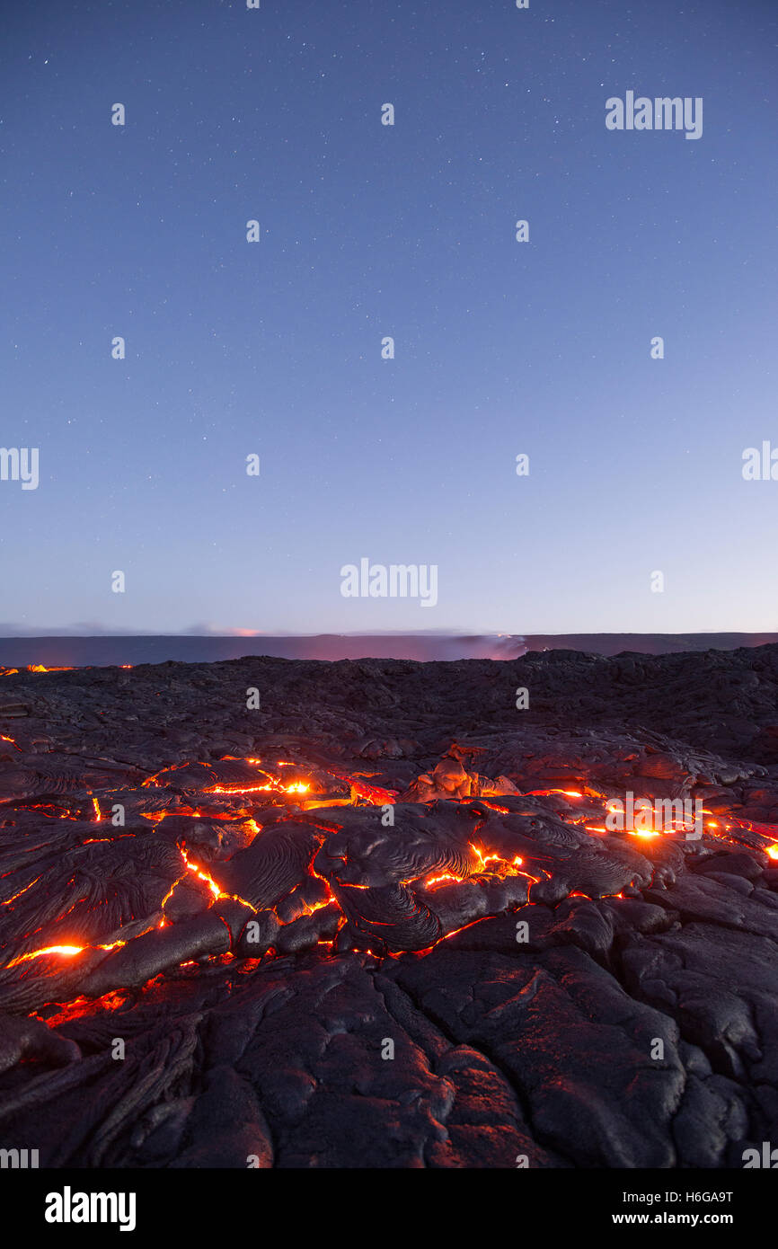 Sternen füllen den Himmel vor der Morgendämmerung als heiße Lava leuchtet durch die Ritzen der Pahoehoe in der Strömung 61 G, Hawaiʻi-Volcanoes-Nationalpark Stockfoto