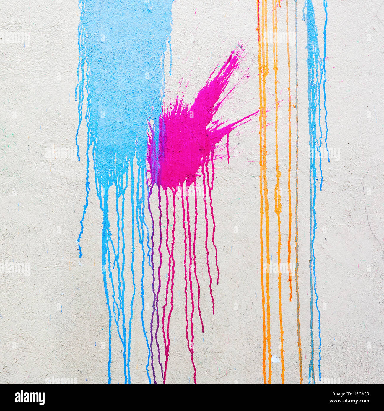 weiße Wand mit bunten Flecken und fließende Farbe Stockfoto
