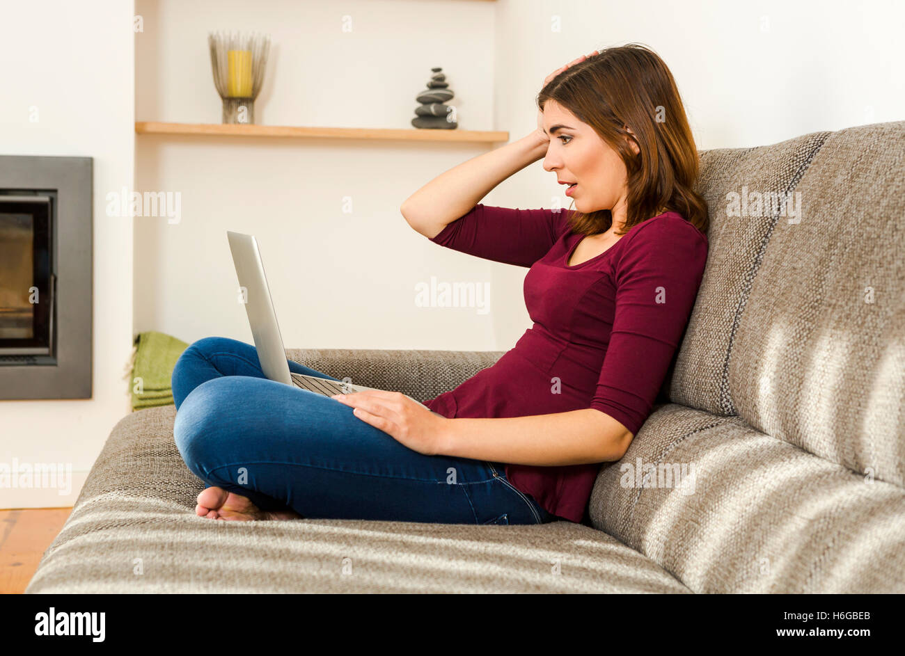 Schöne Frau aus dem Komfort von zu Hause mit ihrem Laptop arbeiten Stockfoto