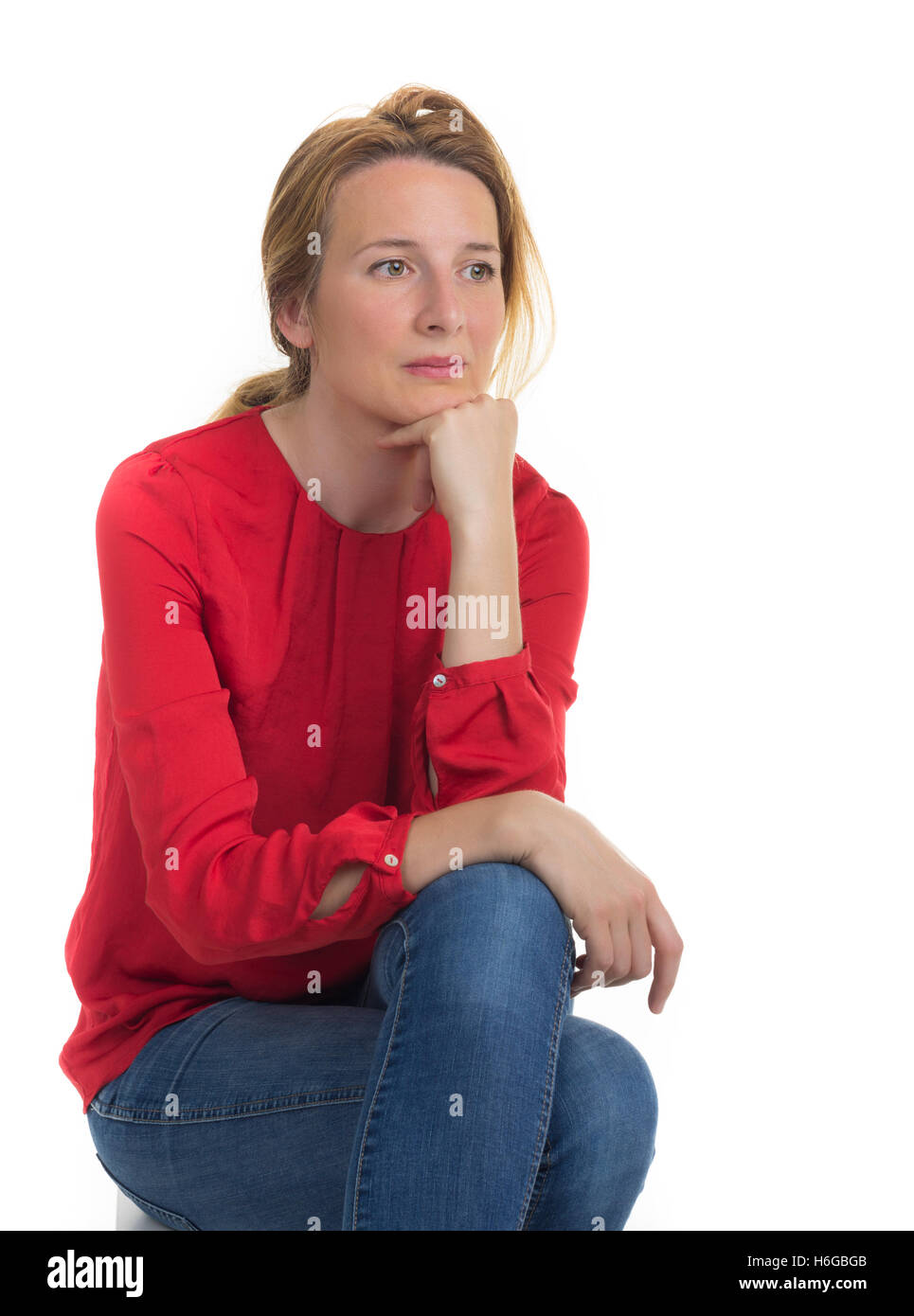 Junge nachdenkliche Frau sitzt auf einem white Cube im Studio. Stockfoto