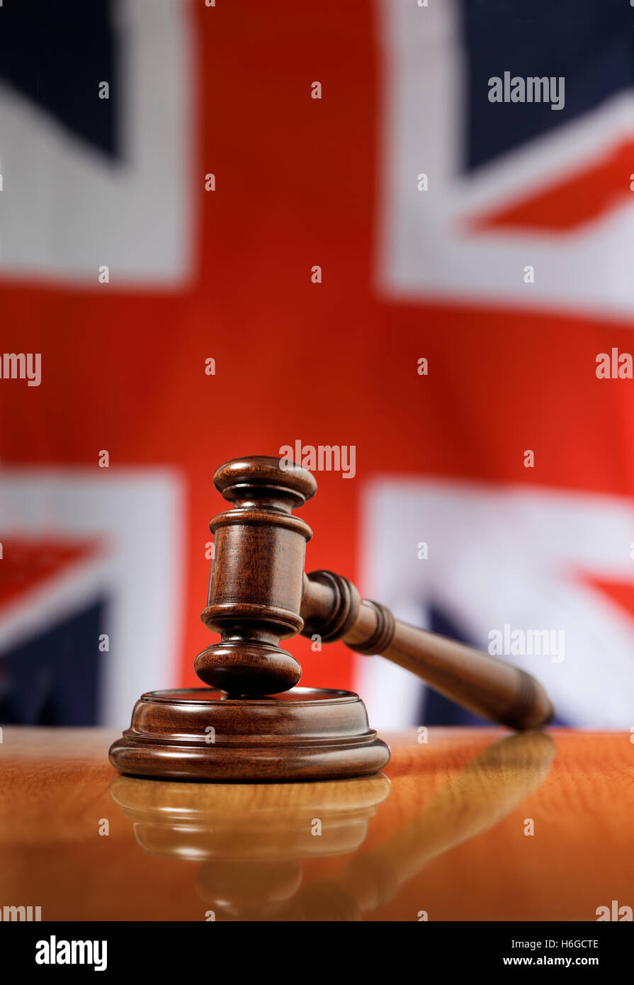 Mahagoni Holz Hammer auf glänzende Holztisch. Flagge des Vereinigten Königreichs im Hintergrund. Stockfoto