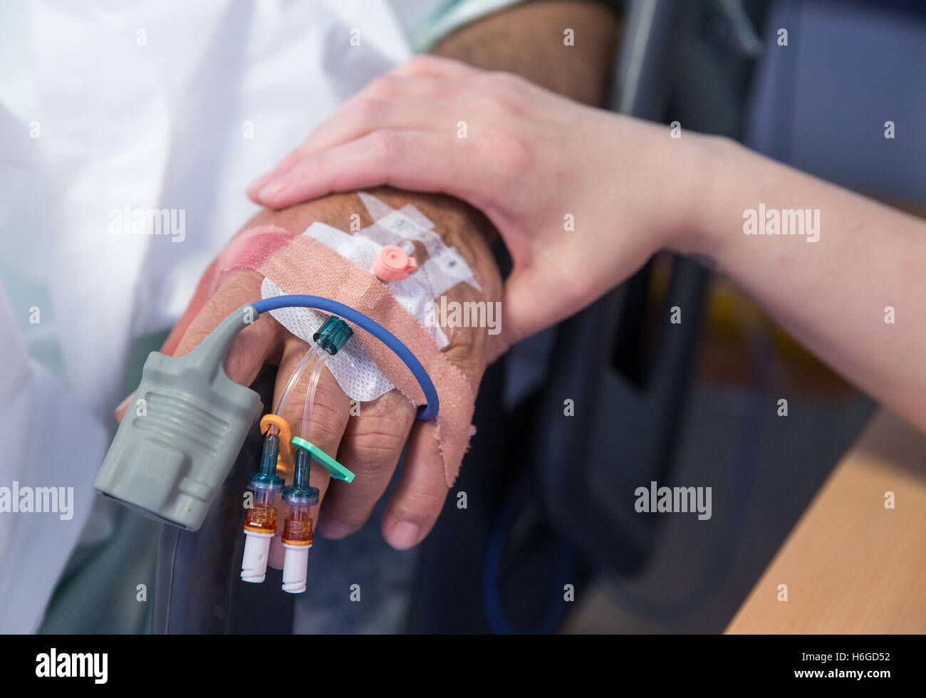 Nahaufnahme der Hand einer Krankenschwester wie sie eine Patienten-Hand mit Tropfen und Pflaster tröstet Stockfoto