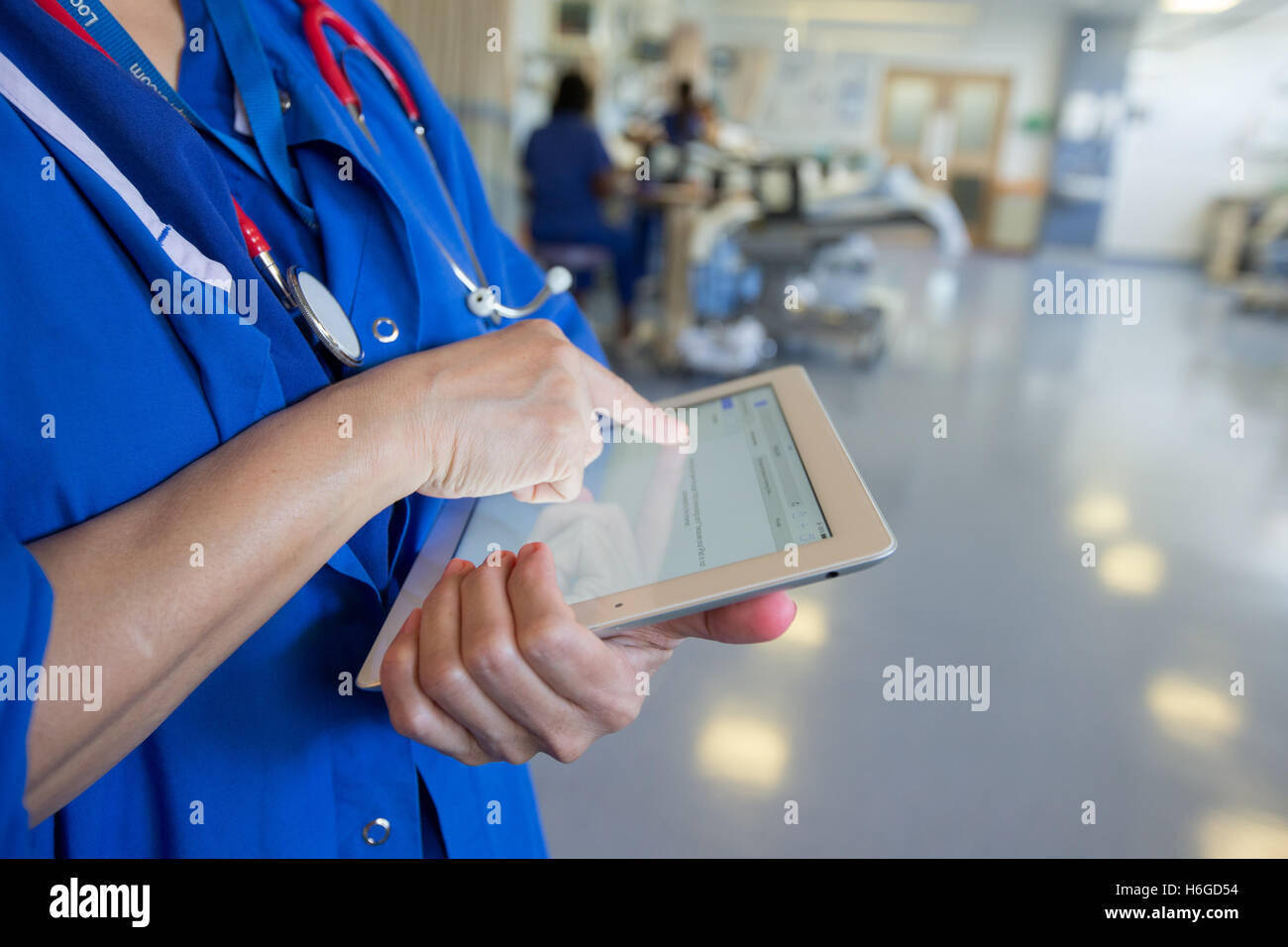 Ein Arzt auf einer Station überprüft eine Patientencharta Datensätze auf einem Ipad Stockfoto