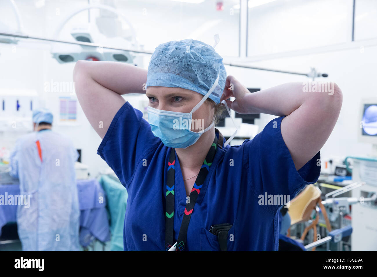 Krankenschwester, binden ihre Maske hinter ihrem Kopf vor einer operation Stockfoto
