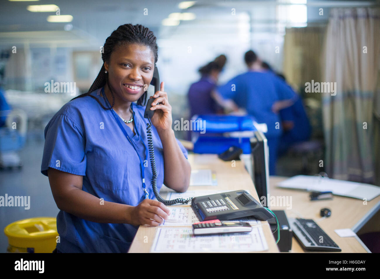 Krankenschwester an einer Workstation in einer Gemeinde, die Beantwortung von Anfragen und medizinische Unterlagen Stockfoto