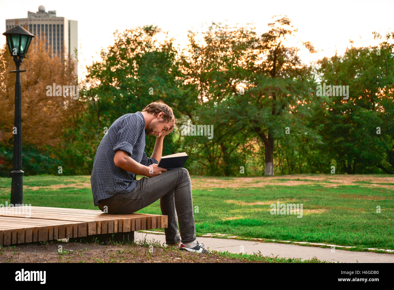 Mann sitzt auf einer Bank im Park Buch Stockfoto