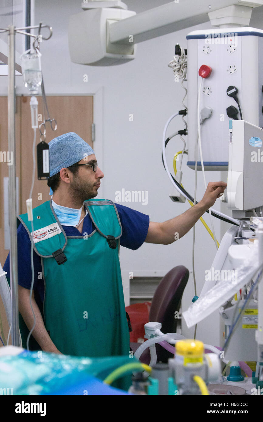 Ein Anästhesist prüft einen medizinischen Tropf während einer Operation in einem Krankenhaus-Theater Stockfoto