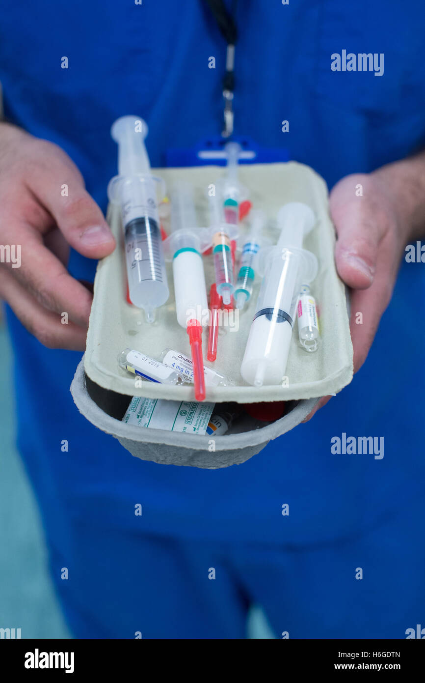 Ein Theater-Techniker hält ein Tablett mit Nadeln bereit, um den Patienten vor einer Operation zu verwalten Stockfoto