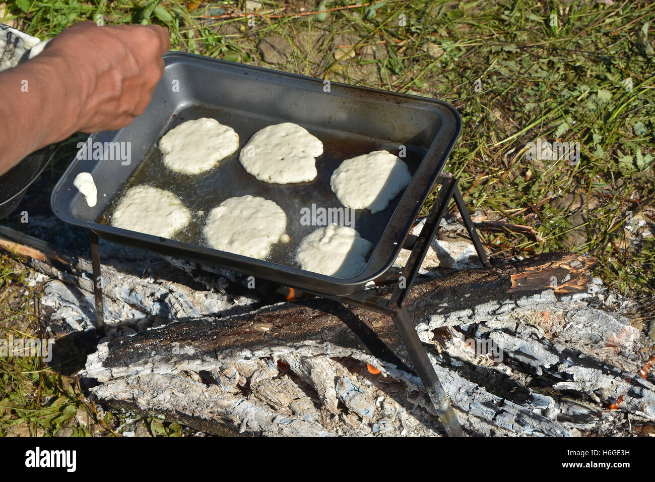 Am Lagerfeuer Kochen Pfannkuchen zum Frühstück. Die Pfanne mit den Tortillas auf dem Feuer. Stockfoto