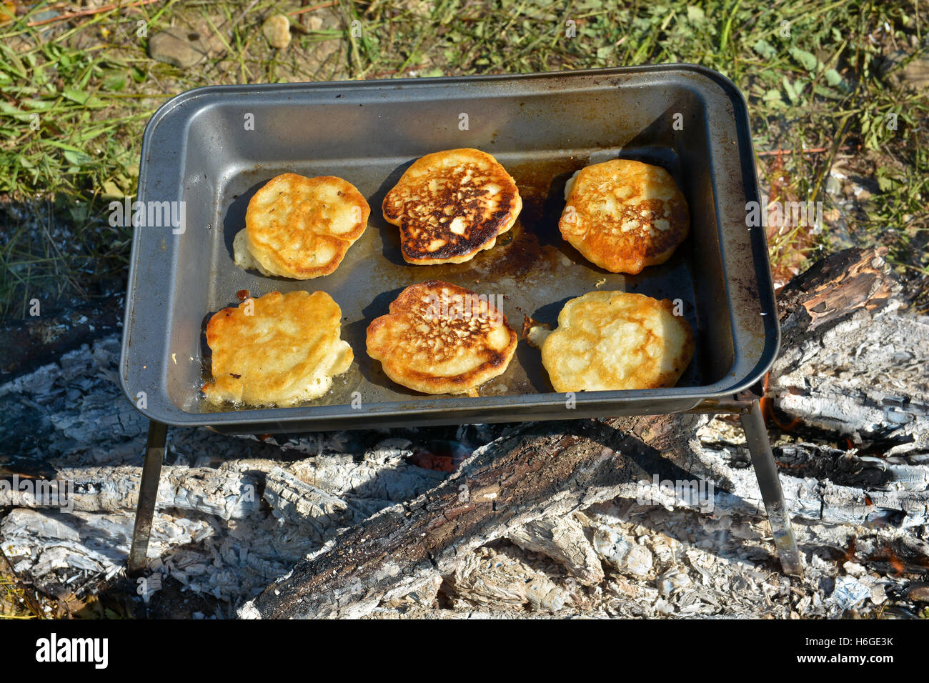 Am Lagerfeuer Kochen Pfannkuchen zum Frühstück. Die Pfanne mit den Tortillas auf dem Feuer. Stockfoto