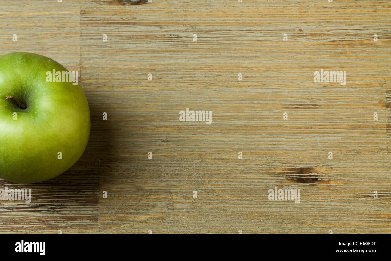 Grüner Apfel auf einem Holztisch halb sichtbar Stockfoto