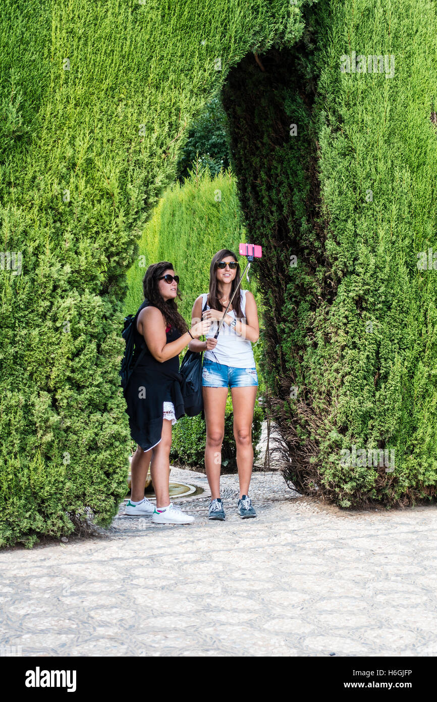 Zwei junge weibliche Touristen nehmen Selfie im Garten der Alhambra, Granada, Spanien. Stockfoto