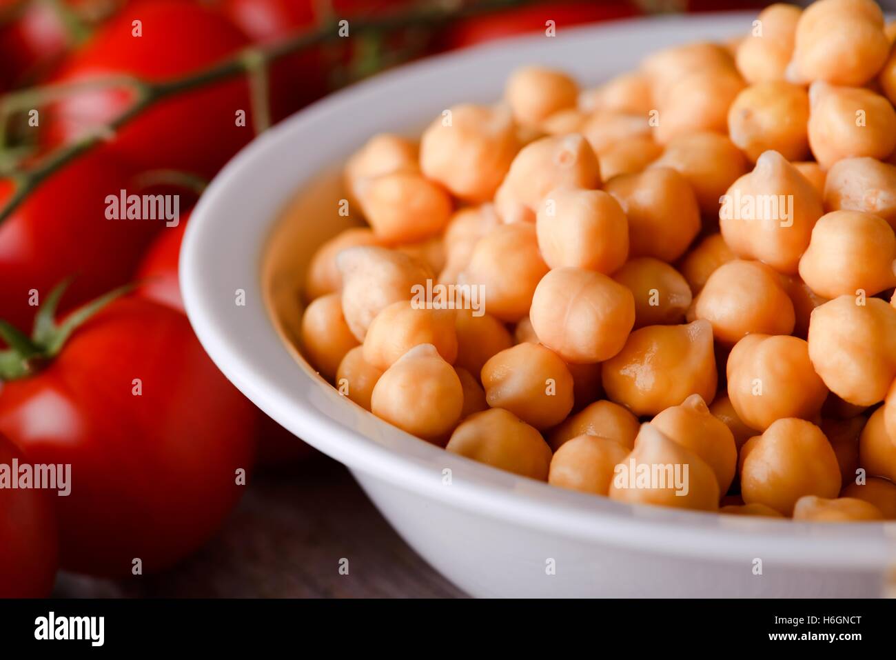 Horizontale Foto der weißen Schale voll orange Kichererbsen-Gemüse. Tomaten und Vollkornbrot sind als nächstes auf hölzernen Eber Schüssel Stockfoto