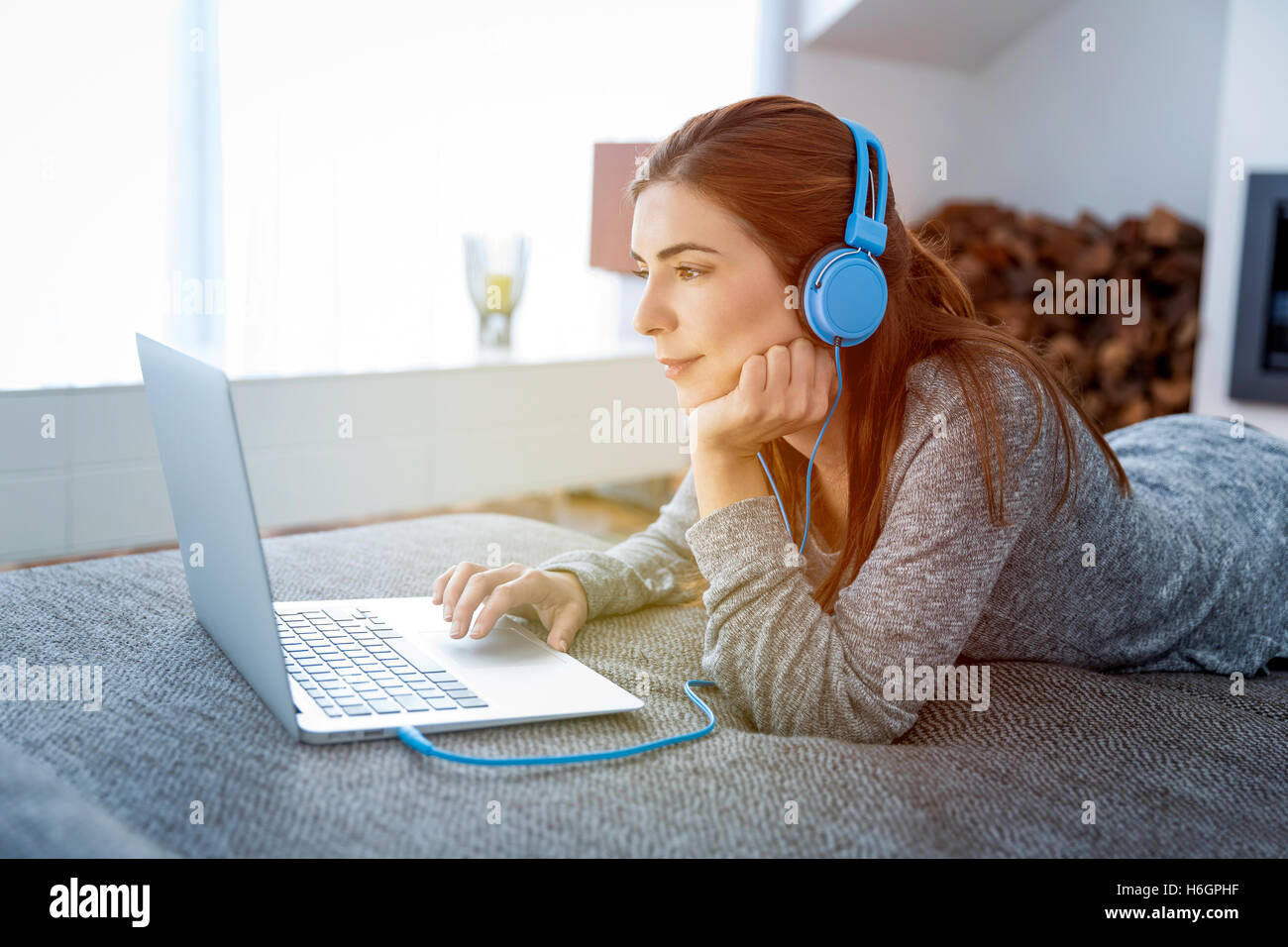 Schöne Frau mit Laptop beim Musik hören zu Hause arbeiten Stockfoto