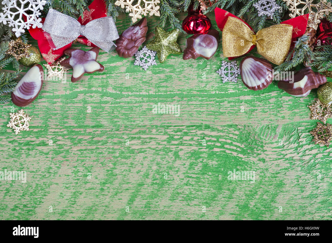 Grüne Weihnachten Hintergrund auf eine Holzoberfläche, viel Platz für die Beschriftung. Zweige Wacholder, Baumschmuck und Schokolade. Stockfoto