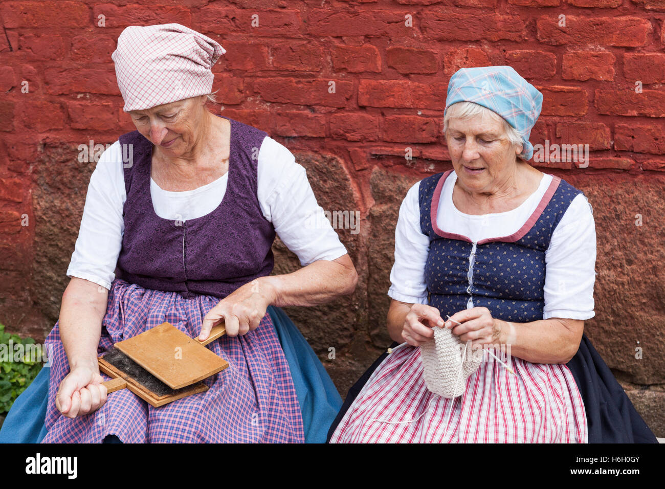 Zwei Damen gekleidet in traditioneller Tracht kardieren und stricken, Den Gamle By, Aarhus (Dänemark) Stockfoto