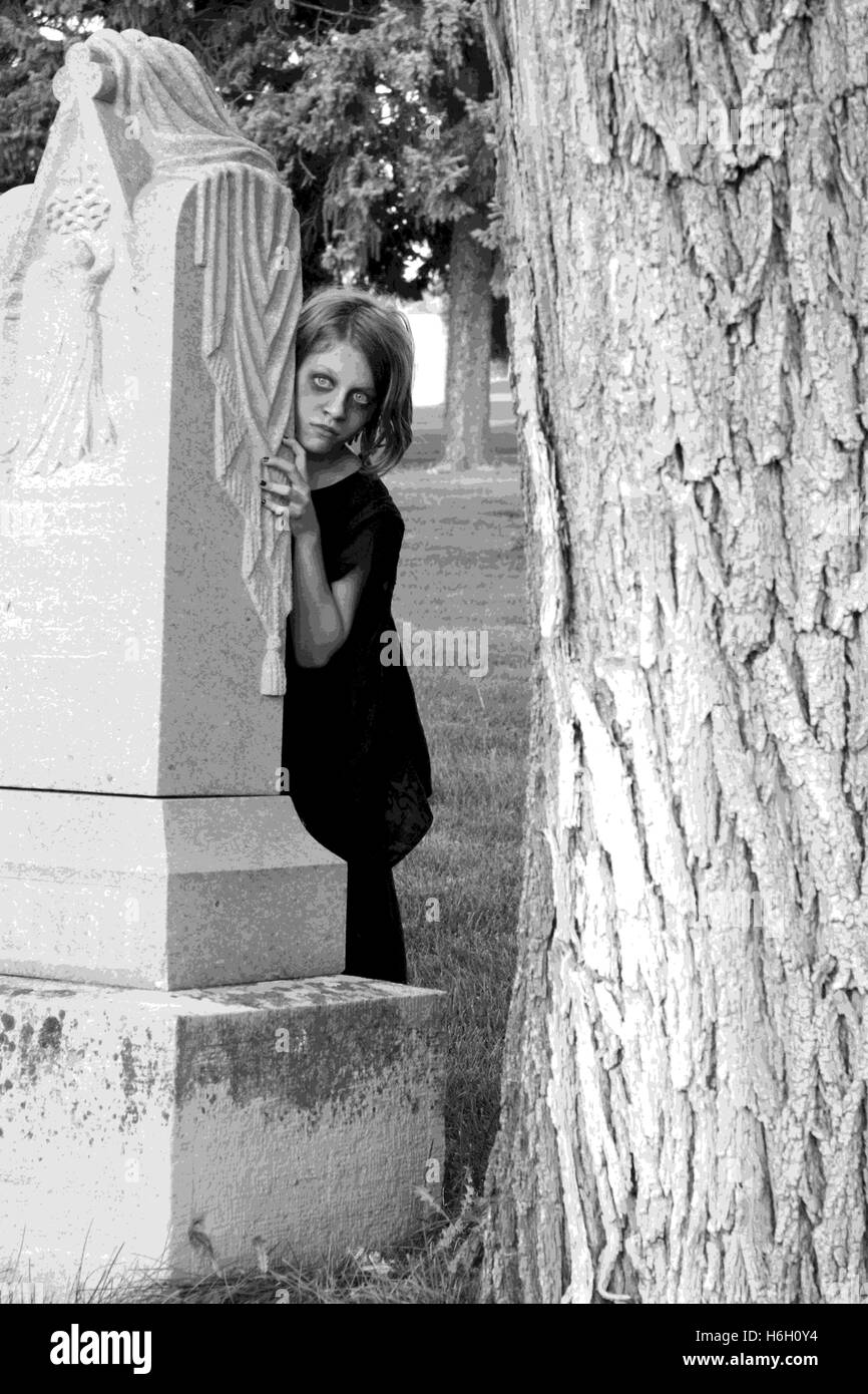 Das gespenstische Mädchen neben Grab stein im Friedhof. Stockfoto