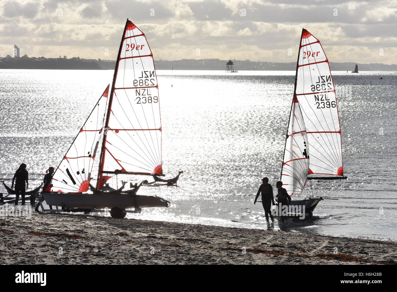 Racing Segelboote mit transparenten Segeln am Strand mit Meer Oberfläche reflektierende Abendsonne im Hintergrund. Stockfoto