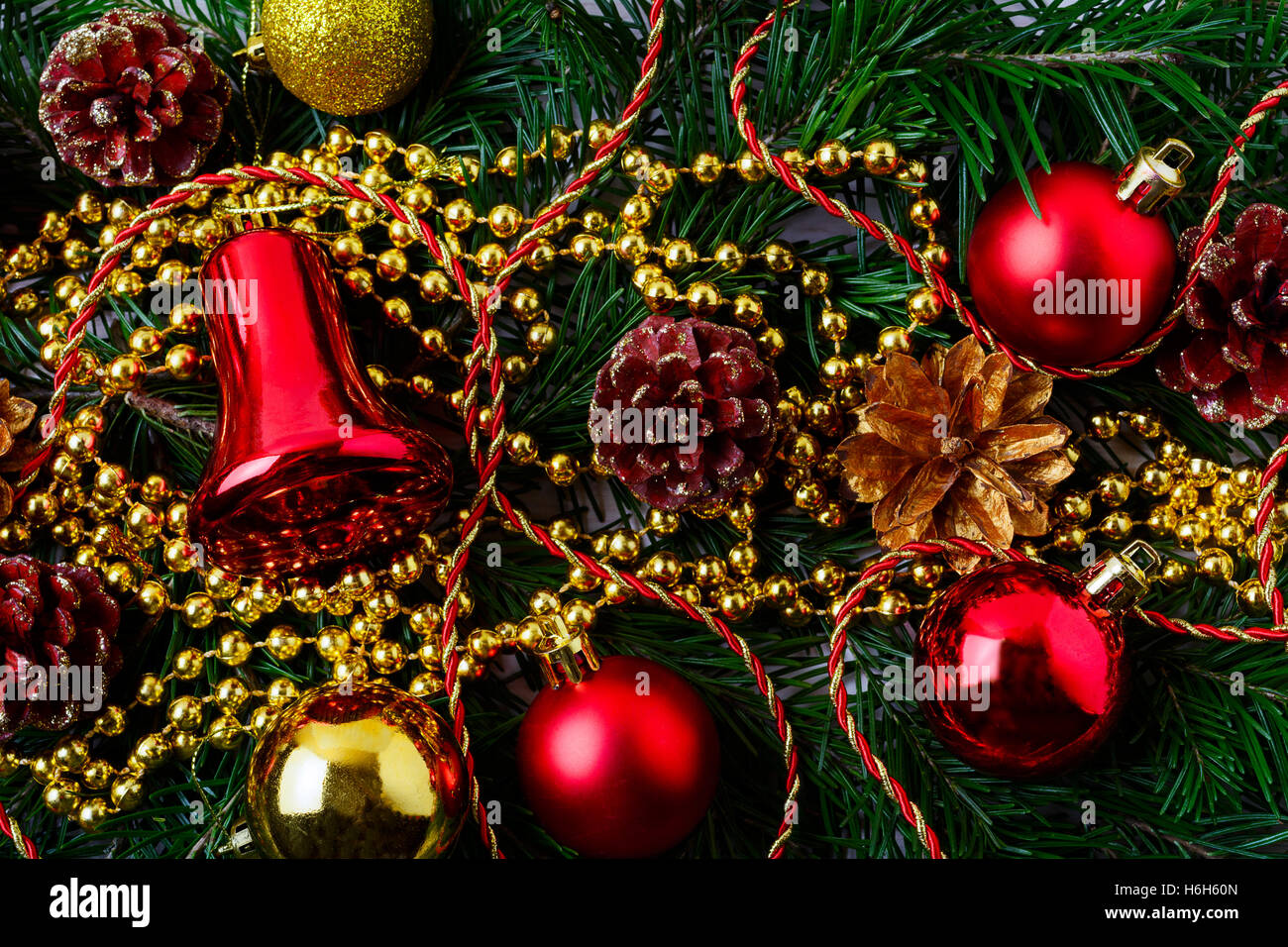 Weihnachten Hintergrund mit goldenen Tannenzapfen und roten Ornamenten. Weihnachts-Party-Dekoration mit glänzenden Kugeln. Gruß zu Weihnachten Stockfoto