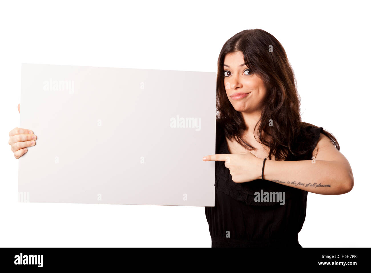 Schöne junge Erwachsene kaukasischen Frau in ihrem Mitte 20 mit einem süßen Lächeln auf ihrem Gesicht in die Kamera schaut, hält eine leere weiße Stockfoto