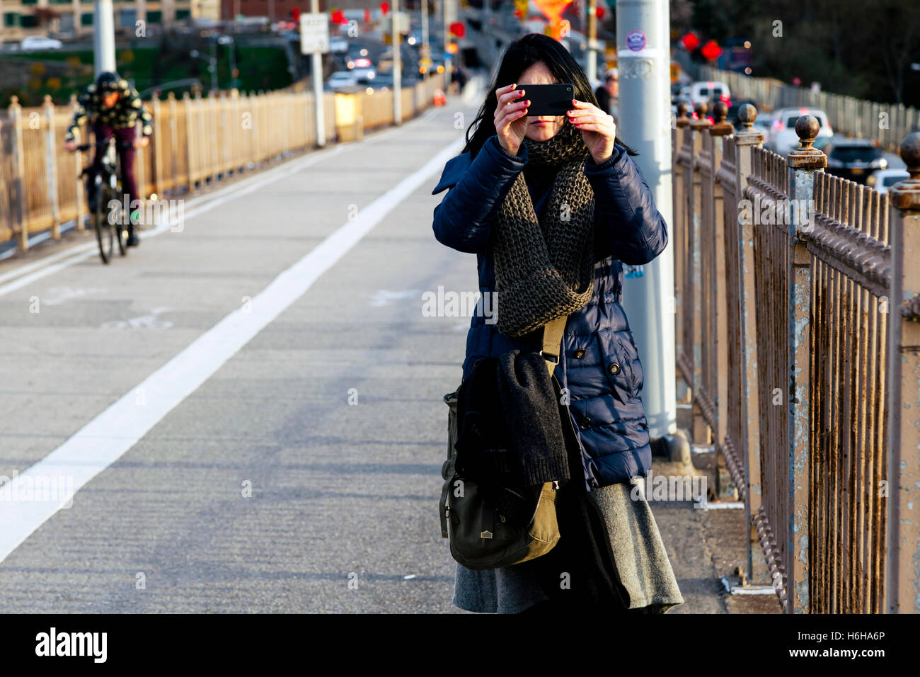 Erwachsene Frau, stehend auf der Brooklyn Ausgangspunkt der Brooklynbridge, Fotografieren mit ihrem Smartphone. Stockfoto